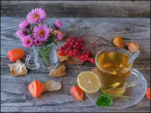 Filiżanka herbaty i jagody obok bukietu kwiatów