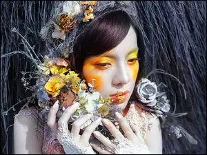 Kobieta w makijażu przytula kwiaty do twarzy