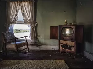 Zaniedbane wnętrze ze zniszczonym telewizorem i rozwalającym się krzesłem