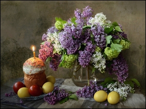 Kompozycja z pisankami na talerzyku, babeczką i kwiatami bzu w wazonie
