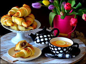 Filiżanka herbaty z imbryczkiem rogali i bukiet tulipanów