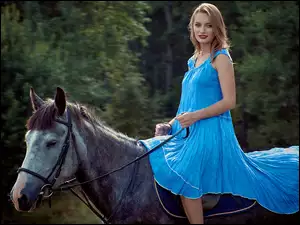 Dziewczyna w niebieskiej sukience na koniu