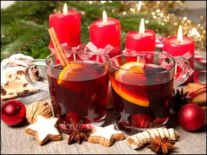 Grzane wino w szklankach i świece w świątecznej kompozycji na stole