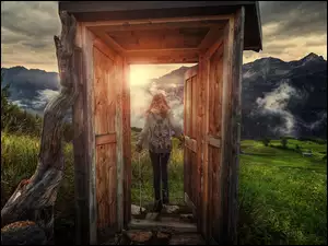 Dziewczyna w drzwiach budki wychodząca na górski szlak