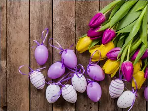 Wielkanocne pisanki z kokardkami obok kolorowych tulipanów