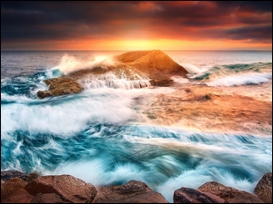 Morze ze skałami i falami o zachodzie słońca
