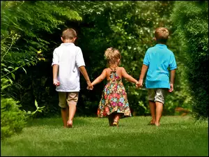 Dzieci trzymając się za ręce spacerują po parku