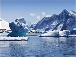 Góra lodowa na morzu otoczona zaśnieżonymi górami