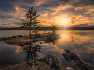 Wschód słońca nad jeziorem z wysepkami i drzewami