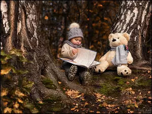 Dziecko z książką i pluszakiem w lesie
