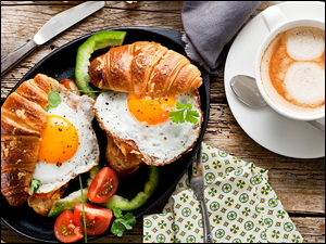 Rogaliki i jajka sadzone obok filiżanki kawy
