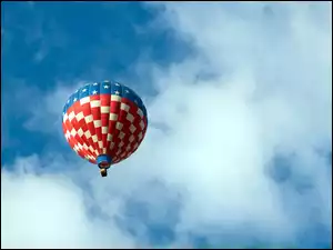 Kolorowy balon między chmurami