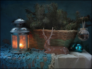 Lampion obok koszyka z gałązkami i figurki jelonka
