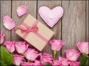 Różowe róże, prezent i gałgankowe serce w kompozycji na deskach