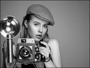 Kobieta w czapce i aparatem fotograficznym z lampą w dłoniach