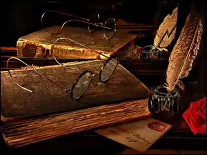 Stara książka z okularami obok kałamarza z piórem i różą przeglądają się w lustrze