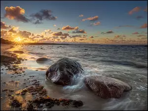 Kamienie na plaży w promieniach zachodzącego słońca