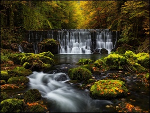 Wodospad spadajÄcy po omszaĹej skale w jesiennym lesie