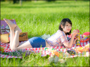 Kobieta leżąca na kocu z koszem piknikowym
