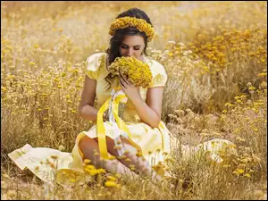Kobieta w wianku i bukietem kwiatów na łące