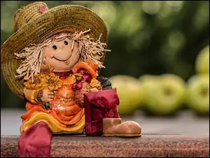 Śmieszna lalka w kapeluszu siedzi na murku