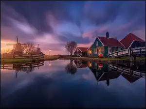 Wiatraki i domy nad rzeką w holenderskim Zaanse Schans o zmierzchu