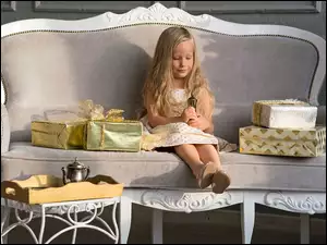 Dziewczynka z prezentami na sofie