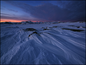 Zachód Słońca nad górskimi śnieżnymi zaspami