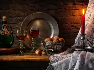 Zapalona świeca obok orzechów kieliszków z winem i ozdobnej karafki