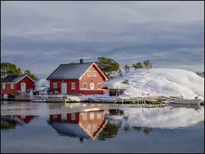Czerwone domki na zaśnieżonym wzgórzu nad jeziorem