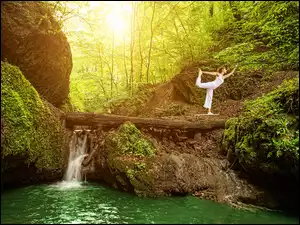 Kobieta ćwicząca jogę w lesie koło wodospadu
