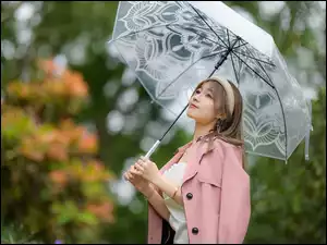 Kobieta w różowym płaszczu z parasolem