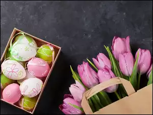 Pisanki w pudełku obok mokrych tulipanów w torbie papierowej
