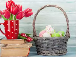 Czerwone tulipany w kubku na książkach obok koszyczka