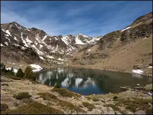 Lekko ośnieżone góry nad jeziorem Tristaina w Andorze