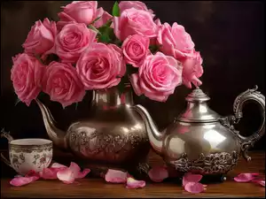 Srebrny czajnik i filiżanka obok róż w srebrnym dzbanku