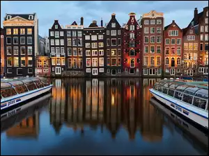 Statki rzeczne i odbicie domów w kanale wodnym w Amsterdamie