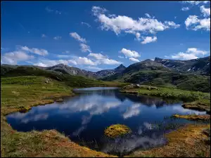 Niebo z białymi obłokami na jeziorem i górami w norweskim okręgu Nordland