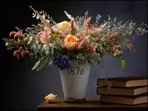 Wazon na stole z bukietem kwiatów obok książek