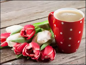 Bukiet tulipanów obok filiżanki kawy na desce