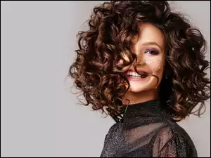 Uśmiechnięta brunetka z kręconymi włosami