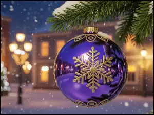 Ozdobna fioletowa bombka na ośnieżonej gałązce na tle oświetlonych domów i zapalonych latarń