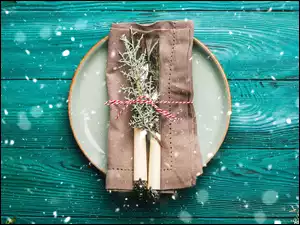 Na zielonym deskach talerz z nożem i widelcem owinięte serwetką do serwowania