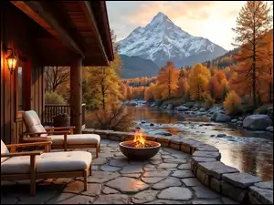 Fotele i ogień na tarasie domu oraz jesienne drzewa nad górską rzeką