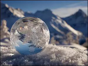 Szklamna kula z wzorami w śnieżynki na śniegu