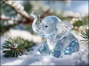 Szklany niebieski słonik na śniegu obok gałązek sosny