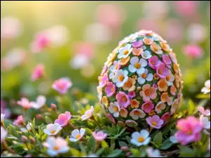 Jajko pokryte drobnymi kolorowymi kwiatami na ukwieconej łące
