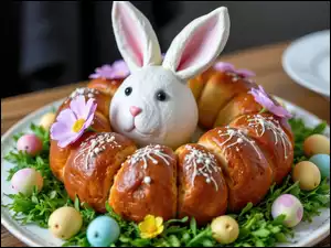 Zajączek w okrągłym chlebie świątecznym otoczonym małymi jajkami na talerzu