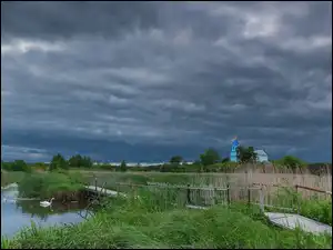 Pomost nad stawem i cerkiew w oddali